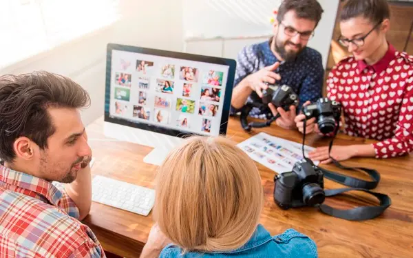 Computador com diversos arquivos de fotos abertos na tela com pessoas na frente do computador