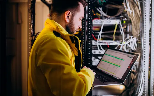 Backup de servidores - homem dentro da área de servidor da empresa conectado ao notebook